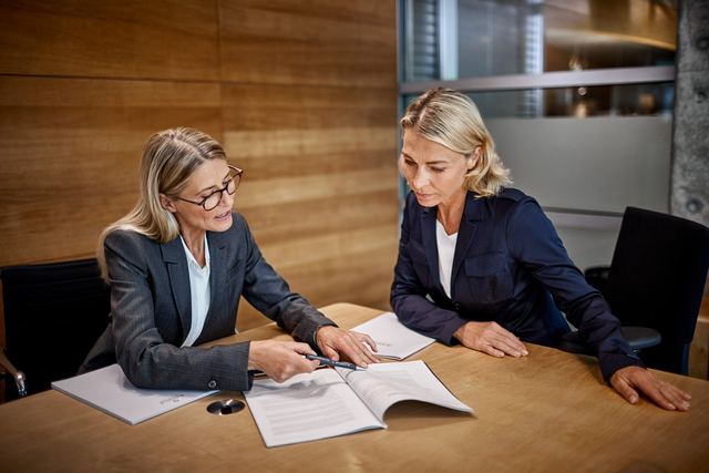 Zwei Kolleginnen arbeiten an Unterlagen